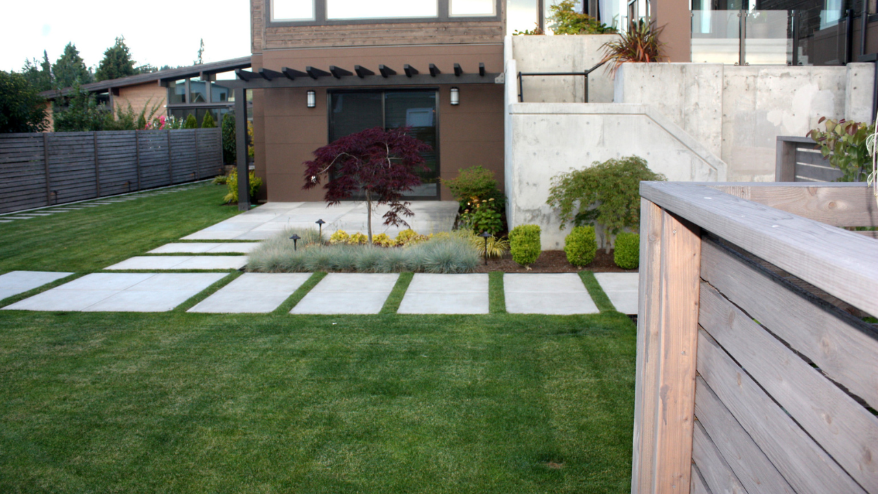 Freshly installed turf lawn with stone walkway and modern fence